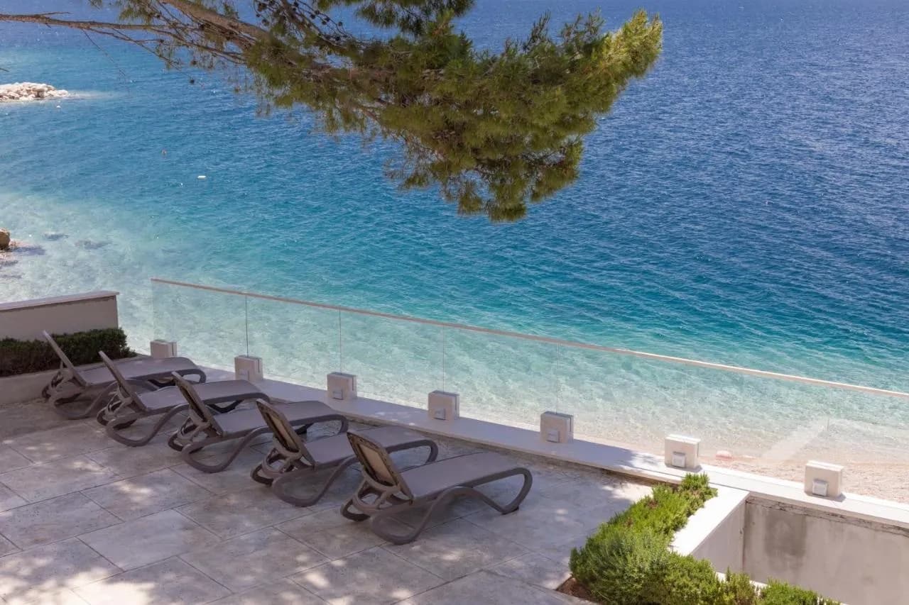 Red ležaljki iza staklene ograde točno iznad plaže, Villa Carica