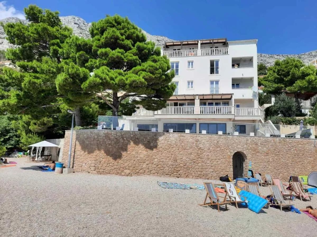 Villa Carica snimljena s plaže — svi balkoni okrenuti moru, krovna terasa s pergolom